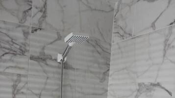 Une douche équipée d’un pommeau de douche à main et de commandes murales.