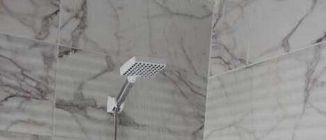 Una dutxa amb un braç de pluja i comandaments fixats a la paret.