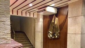 Un pasillo con piso de mármol, una puerta de madera y una escalera al fondo.