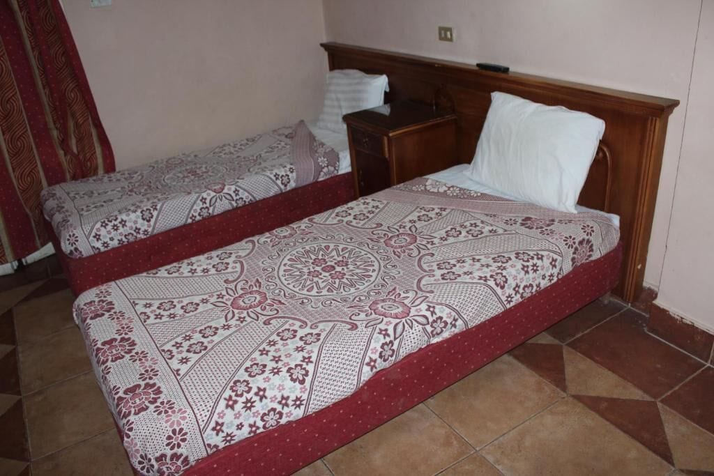 Une chambre avec deux lits, chacun agrémenté de draps à motifs et d’une tête de lit en bois.