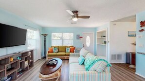 Un salon avec un canapé, une table basse, un téléviseur et un ventilateur de plafond.