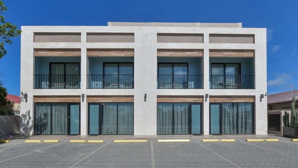 En moderne bygning med en flad facade, flere balkoner og store vinduer.