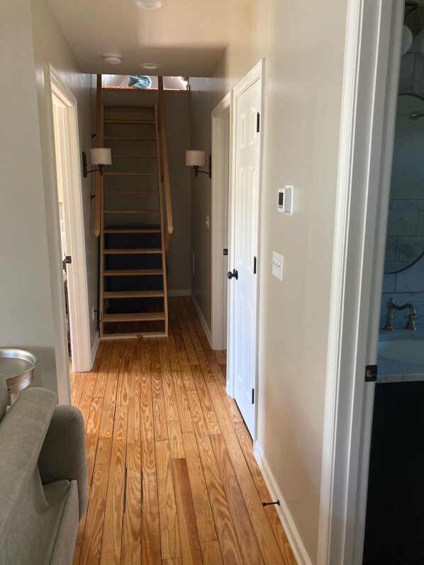 A hallway with wooden flooring, a staircase, and white doors. - Belmont Carriage House (Charlottesville)