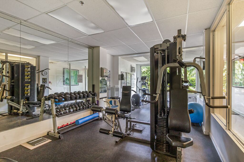 A gym with various exercise equipment, a mirror, and a window with a view of the outdoors.