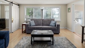 A living room with a grey sofa, a coffee table, and a rug. - Causeway Cottage: Lake Beach & NY Biking Ferry (Colchester)