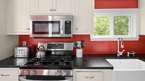 A kitchen with a gas stove, a microwave, a toaster, and a sink.