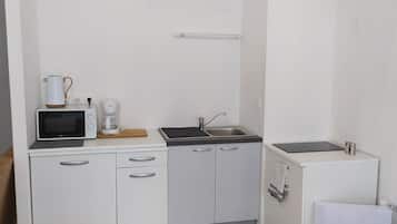 Een koelkast, een kookplaat, kookgerei, borden en bestek