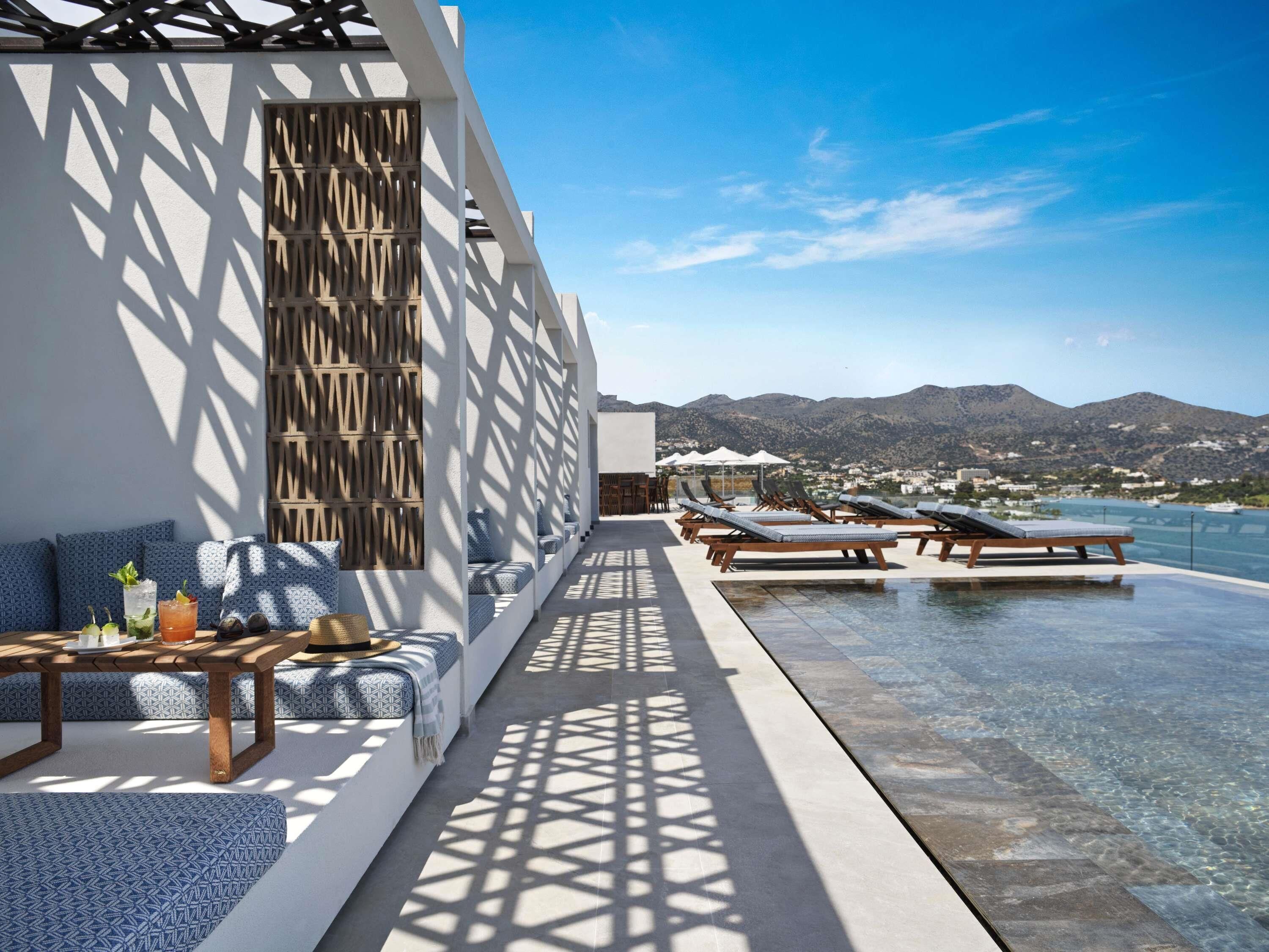 Un espace de détente extérieur moderne, doté d’une piscine, de sièges et offrant une vue sur les montagnes.
