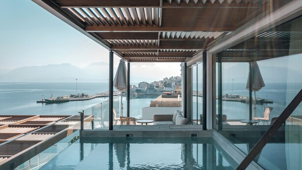 A modern infinity pool with a city view, wooden ceiling, and glass walls.