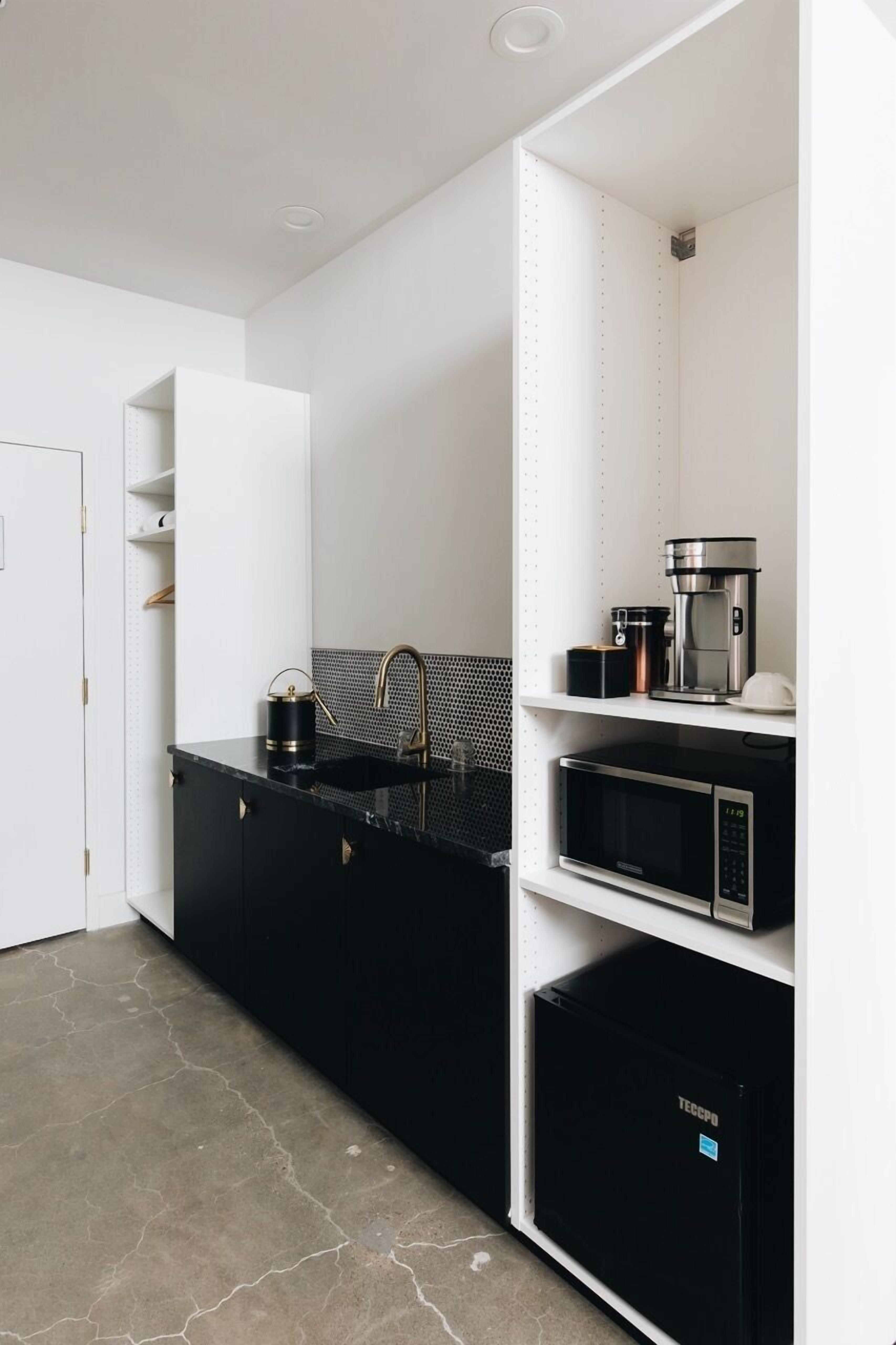 A modern kitchen with black countertops, a sink, a coffee maker, and a microwave.