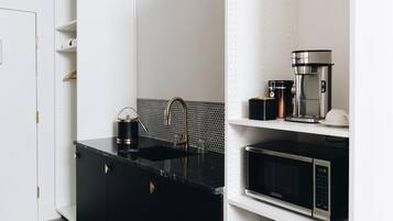 A modern kitchen with black countertops, a sink, a coffee maker, and a microwave.
