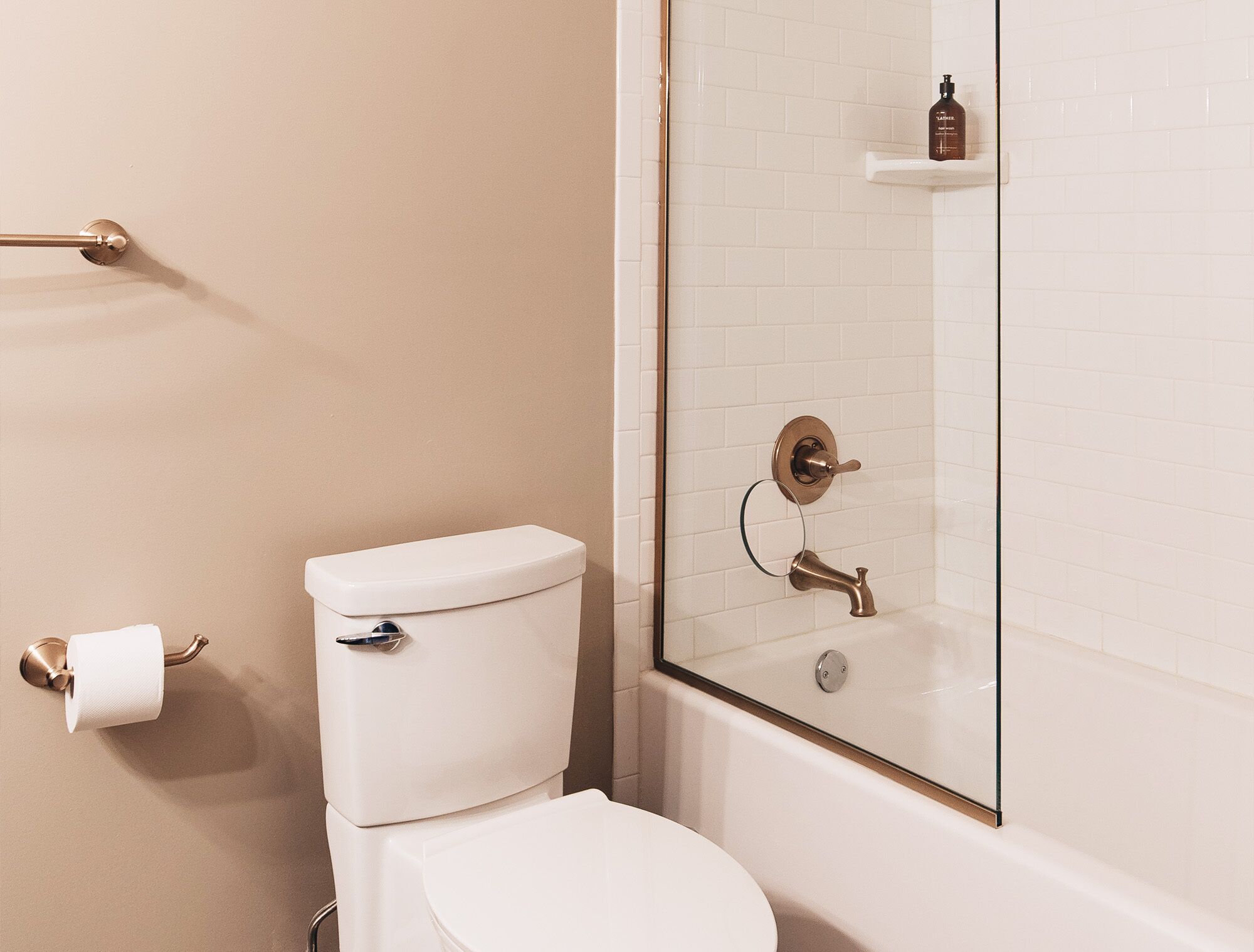 A bathroom with a toilet, a glass shower enclosure, and a white tiled wall.