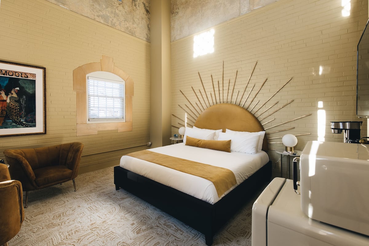 A hotel room with a large bed, a chair, a window, and a wall-mounted radiator.