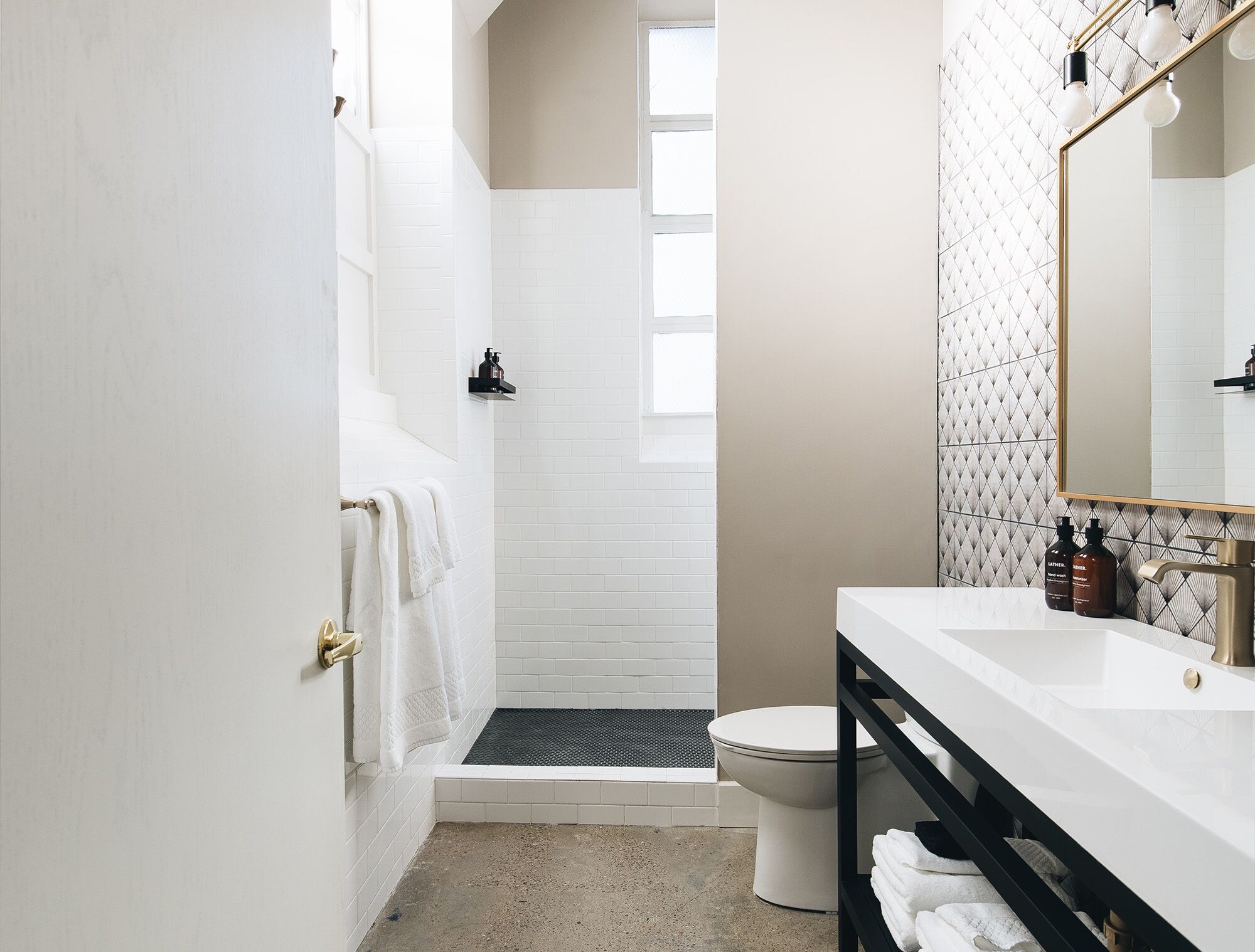 A modern bathroom with a white sink, black vanity, and a shower area.