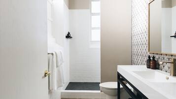 Een moderne badkamer met een wit wastafelmeubel, een zwart aanrecht en een douchehoek.