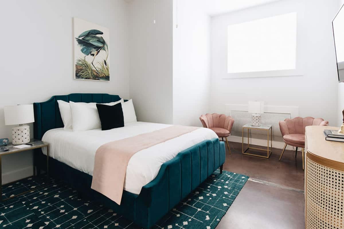A modern bedroom with a bed, bedside tables, a desk, and chairs.