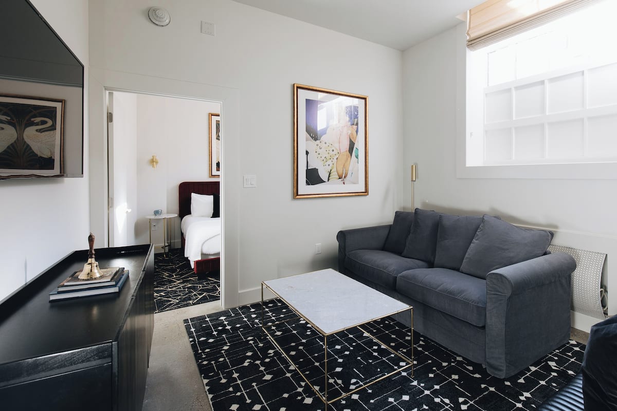 A modern living room with a grey sofa, a coffee table, and a patterned rug.