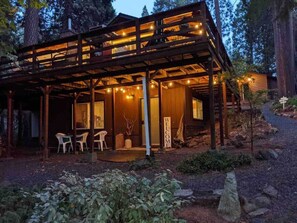 A wooden cabin with a covered porch, a welcome sign, and outdoor seating. - Cozy Cabin Studio in the Pines, Private Entrance, Kitchen, Dogs OK, Walk to Town (Twain Harte)