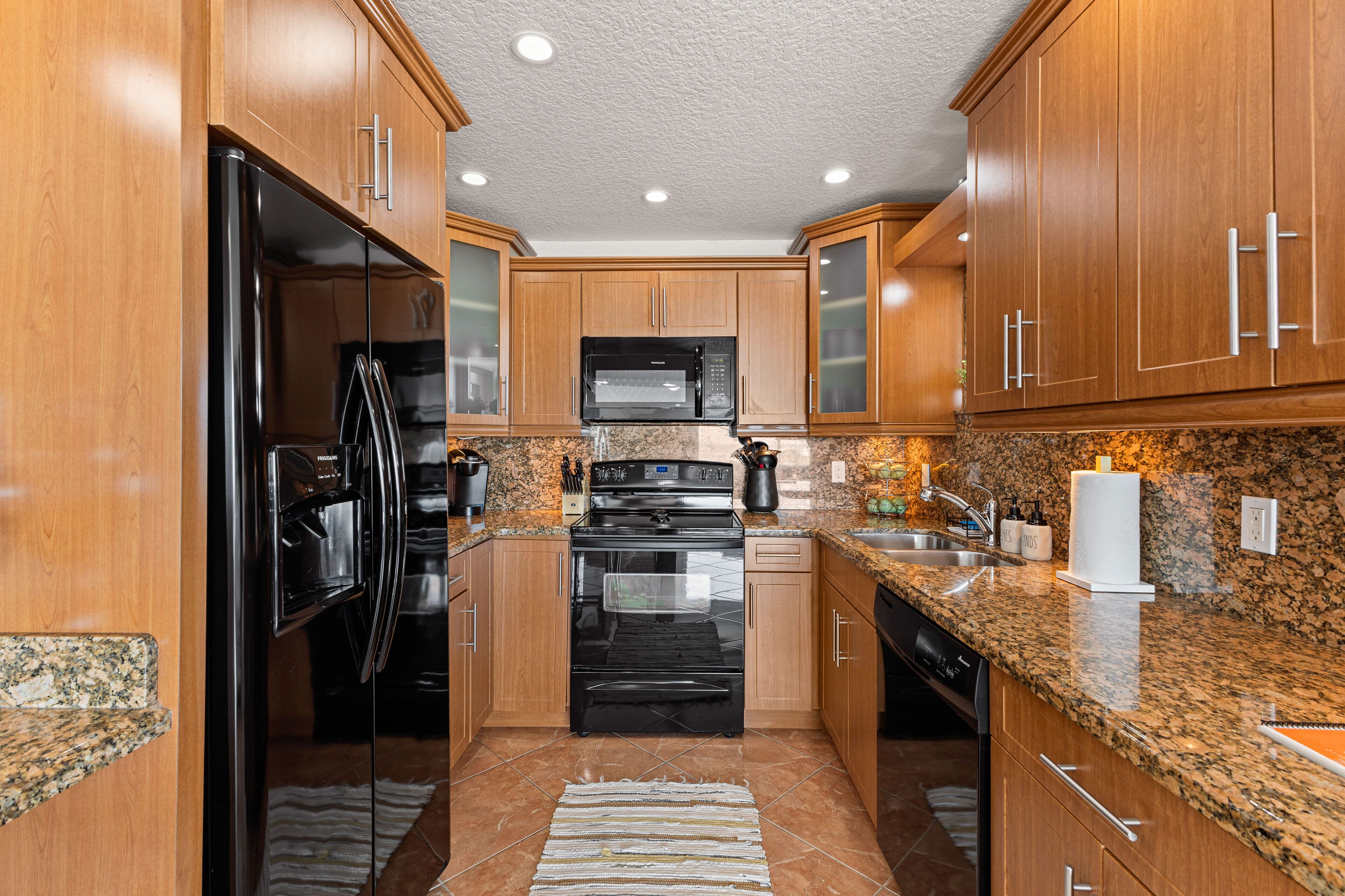 A kitchen with wooden cabinets, a stainless steel refrigerator, a microwave, an oven, and a dishwasher.