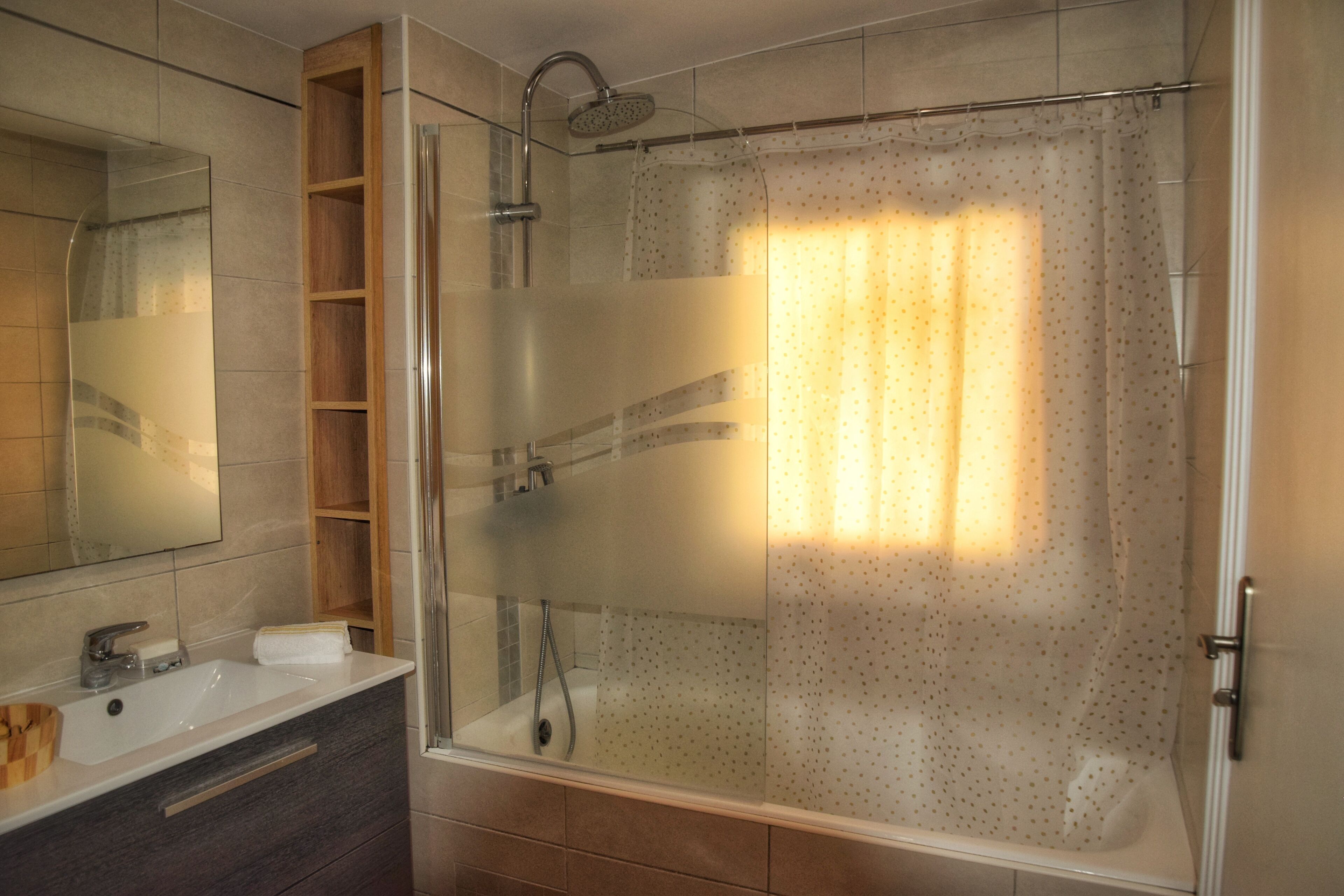 Ein modernes Badezimmer mit einer gläsernen Duschkabine, einem Waschtisch und einem Spiegel.