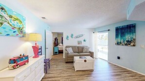 A living room with a sofa, a coffee table, a lamp, a dresser, and a wall with a painting of a turtle. - The Pelican (Nokomis)
