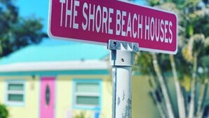A street sign reading "THE SHORE BEACH HOUSES" with a building in the background. - The Pelican (Nokomis)