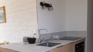 A modern kitchen with a white countertop, wooden cabinets, a stainless steel sink, and a built-in oven. - Les terrasses Plage Benoit, T2 garage box (La Baule-Escoublac)