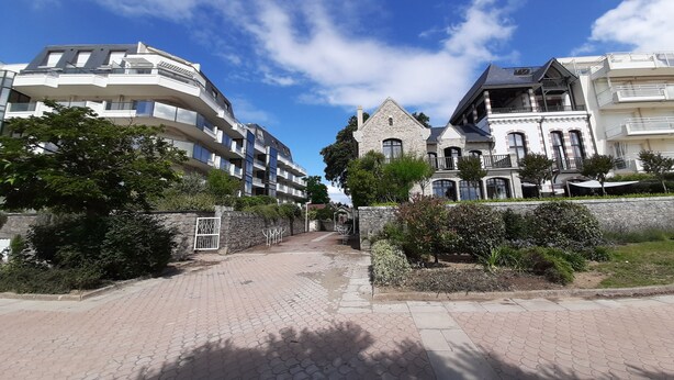 A residential building with multiple balconies, a stone facade, and a paved pathway leading to the entrance. - Les terrasses Plage Benoit, T2 garage box (La Baule-Escoublac)
