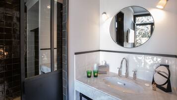 A bathroom with a large mirror, a sink, and a glass-enclosed shower.