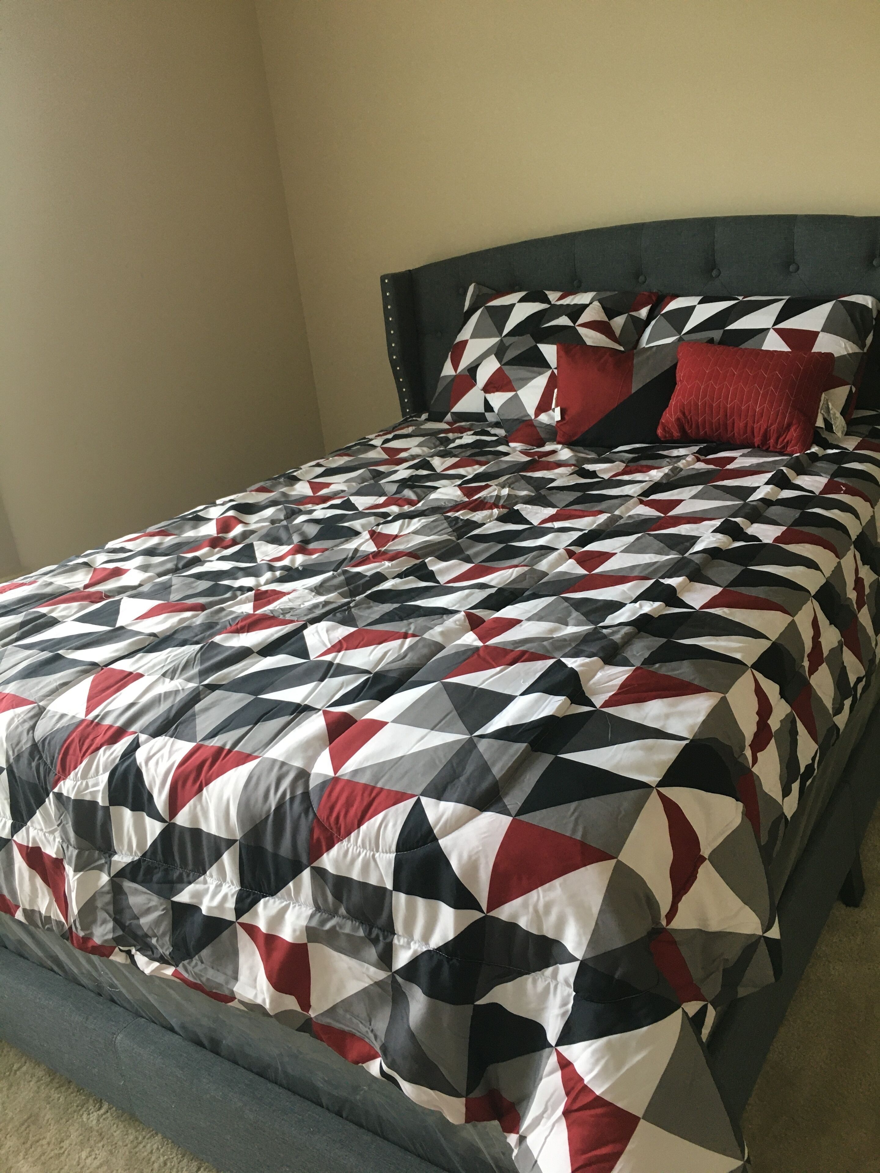 A bed with a geometric patterned bedspread and two pillows.