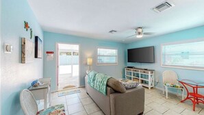 A living room with a sofa, a TV, a small table, and a chair. There is a door leading to another room. - The Dolphin (Nokomis)