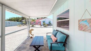 A covered patio area with a blue sofa and a table, a wooden sculpture, and a dolphin wall art piece. - The Dolphin (Nokomis)