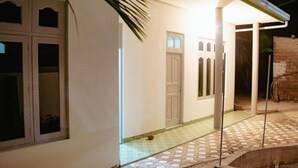 Un edificio con patio empedrado, una puerta y una ventana de varios cristales.