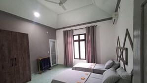 Una habitación con dos camas, un armario, una ventana con cortinas y un ventilador de techo.