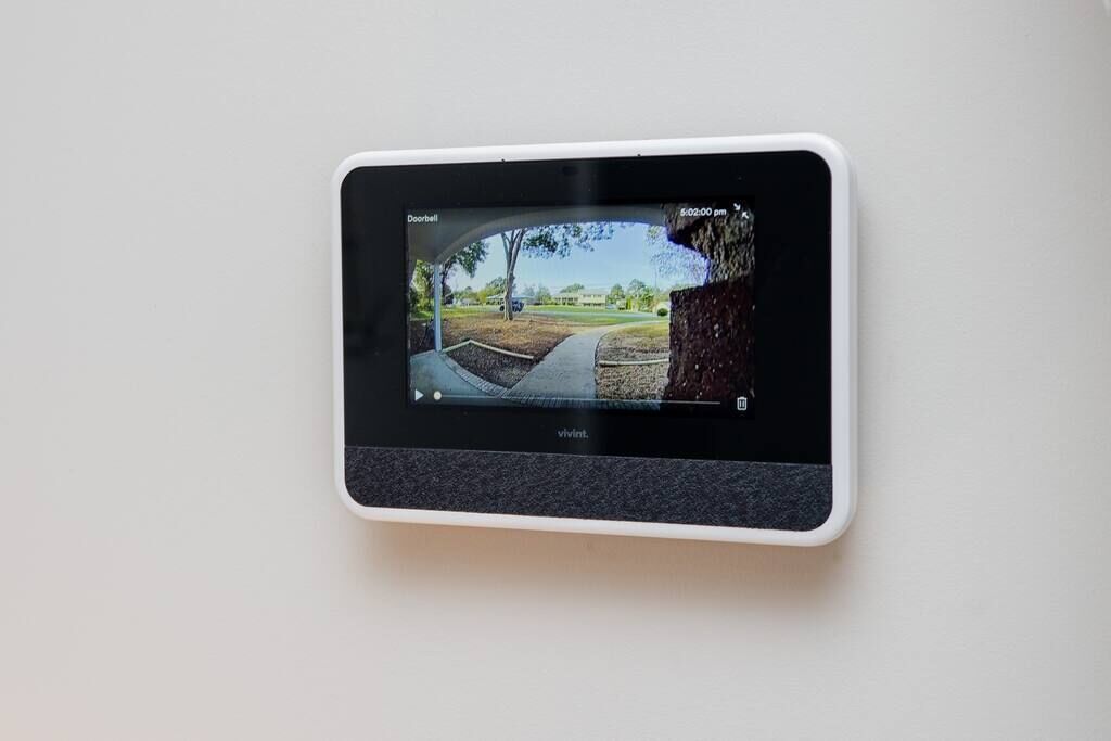 A security camera mounted on a wall, displaying a view of a pathway and trees.