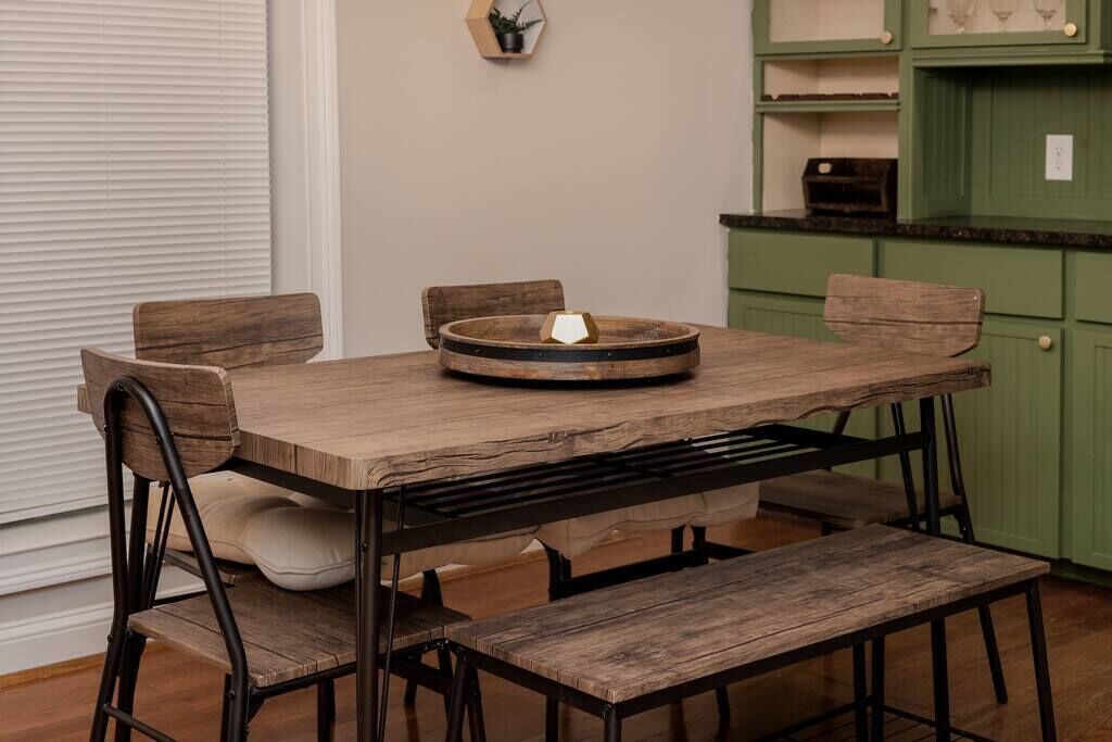 Une table de salle à manger en bois, avec des bancs, un élément décoratif au centre et des meubles de rangement verts en arrière-plan.
