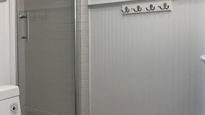 Une salle de bain avec des toilettes blanches, une douche en verre et un mur blanc avec un radiateur.