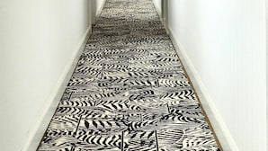 Un couloir doté d’un sol à motifs, de murs blancs et d’un panneau indiquant la sortie.