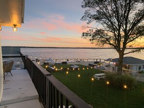 A deck with outdoor seating, a view of the water, and string lights. - Aqua by American Beech - Rooftop Suite (Aquebogue)