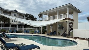 A pool area with lounge chairs, a covered seating area, and a staircase leading to an upper level. - The Salty Snook in Suwannee, FL BEST LOCATION in Complex with Private Boat Slip! (Suwannee)