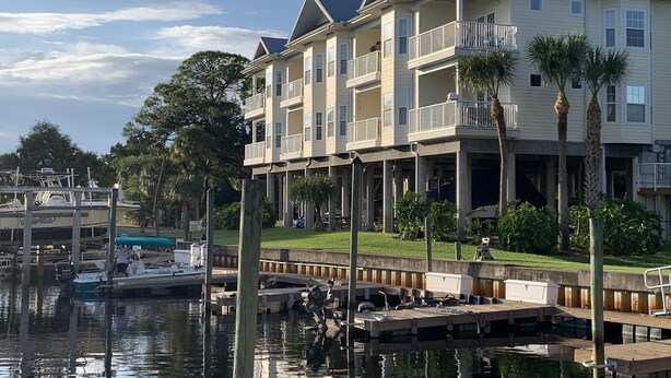 A multi-story building with balconies, a dock, and boats. - The Salty Snook in Suwannee, FL BEST LOCATION in Complex with Private Boat Slip! (Suwannee)
