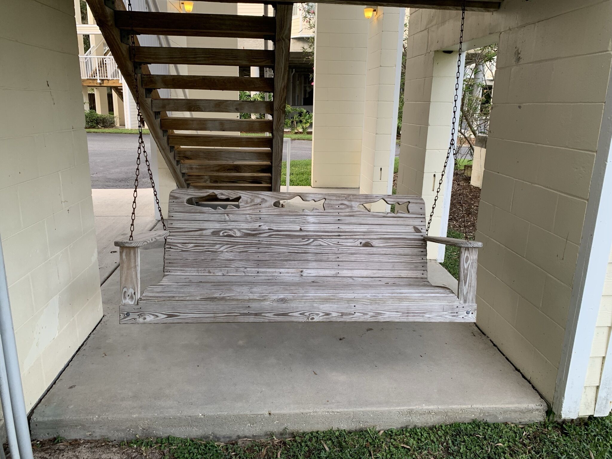 A wooden staircase leading to a covered area with a concrete landing.