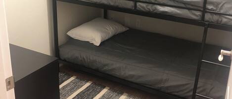 A bunk bed with three levels, each with a pillow and a mattress.