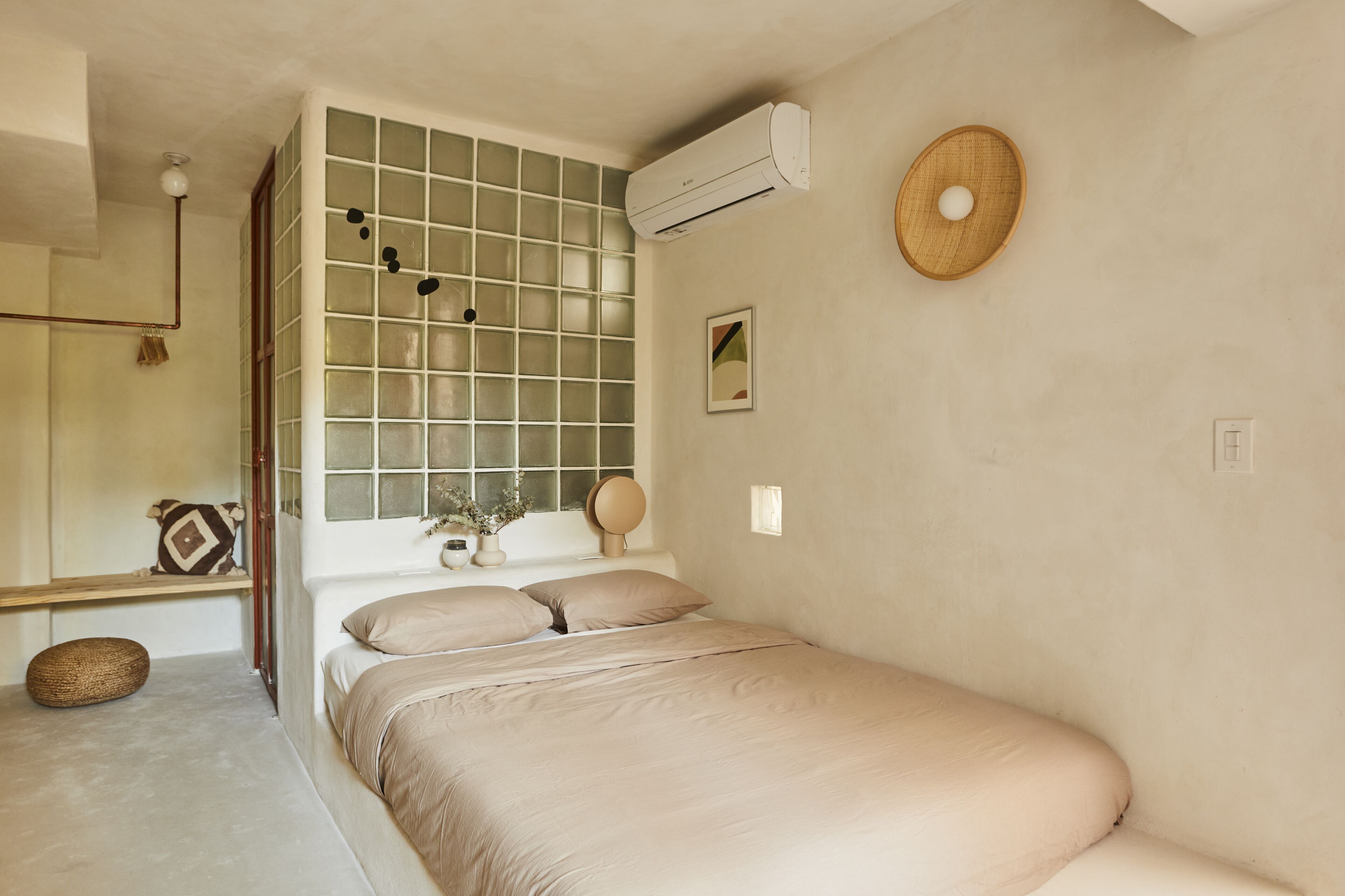 Een slaapkamer met een bed, een raam met uitzicht, een airconditioner en een spiegel aan de muur.