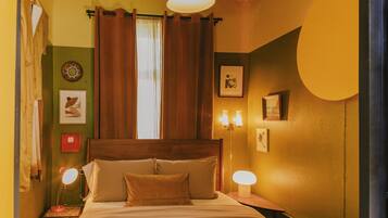 A room with a bed, two bedside lamps, a window with curtains, and wall decorations.