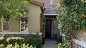 A house with a stone facade, a black front door, and a pathway leading to the entrance.