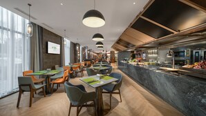 A modern restaurant with a long counter, multiple tables, and chairs. - Holiday Inn Changchun Jingyue by IHG (Changchun)