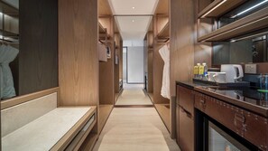 A modern hotel room with a wooden interior, a kitchenette, and a view of the hallway. - Holiday Inn Changchun Jingyue by IHG (Changchun)