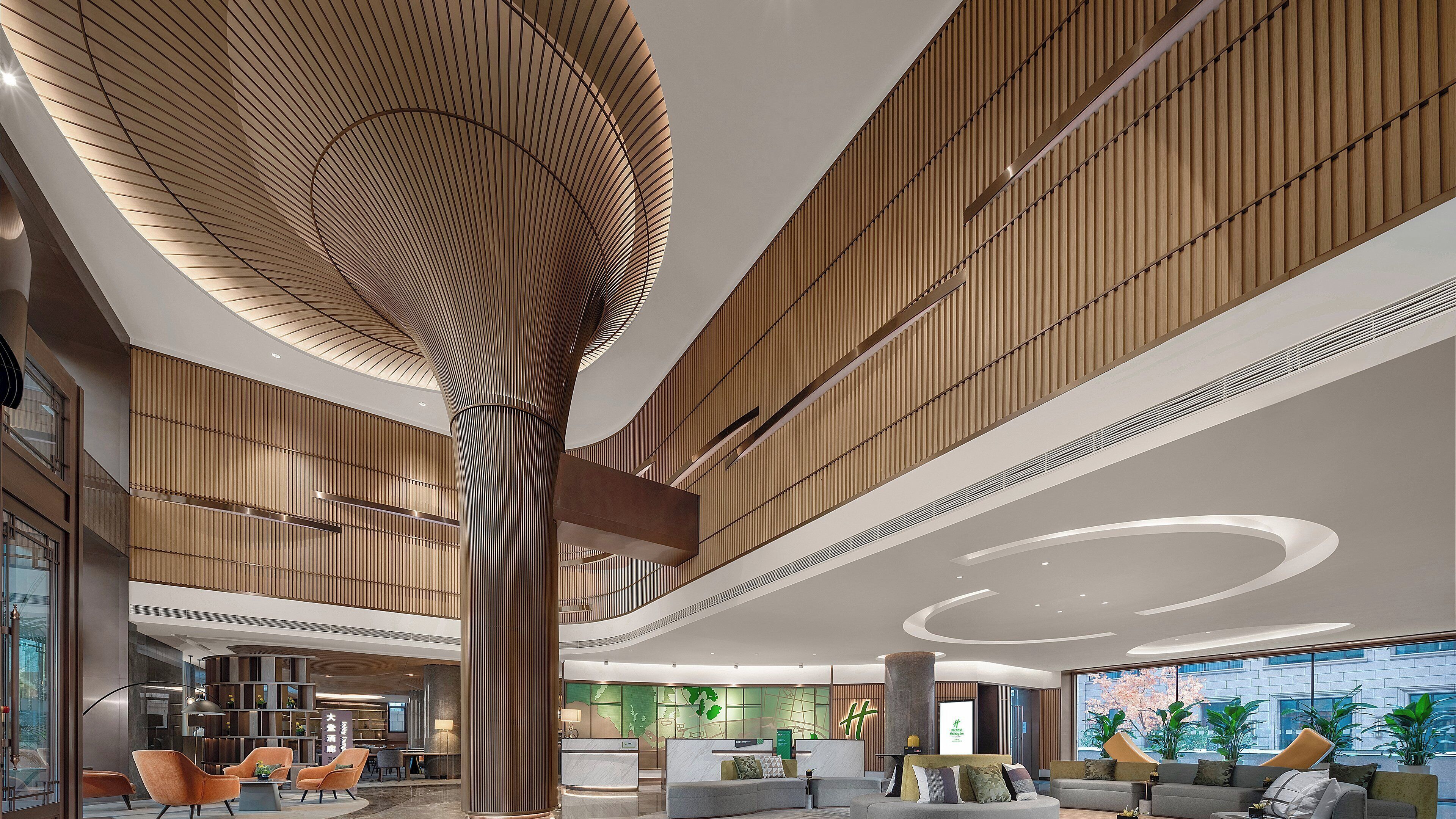 A modern lobby with a central column, seating areas, and a reception desk.
