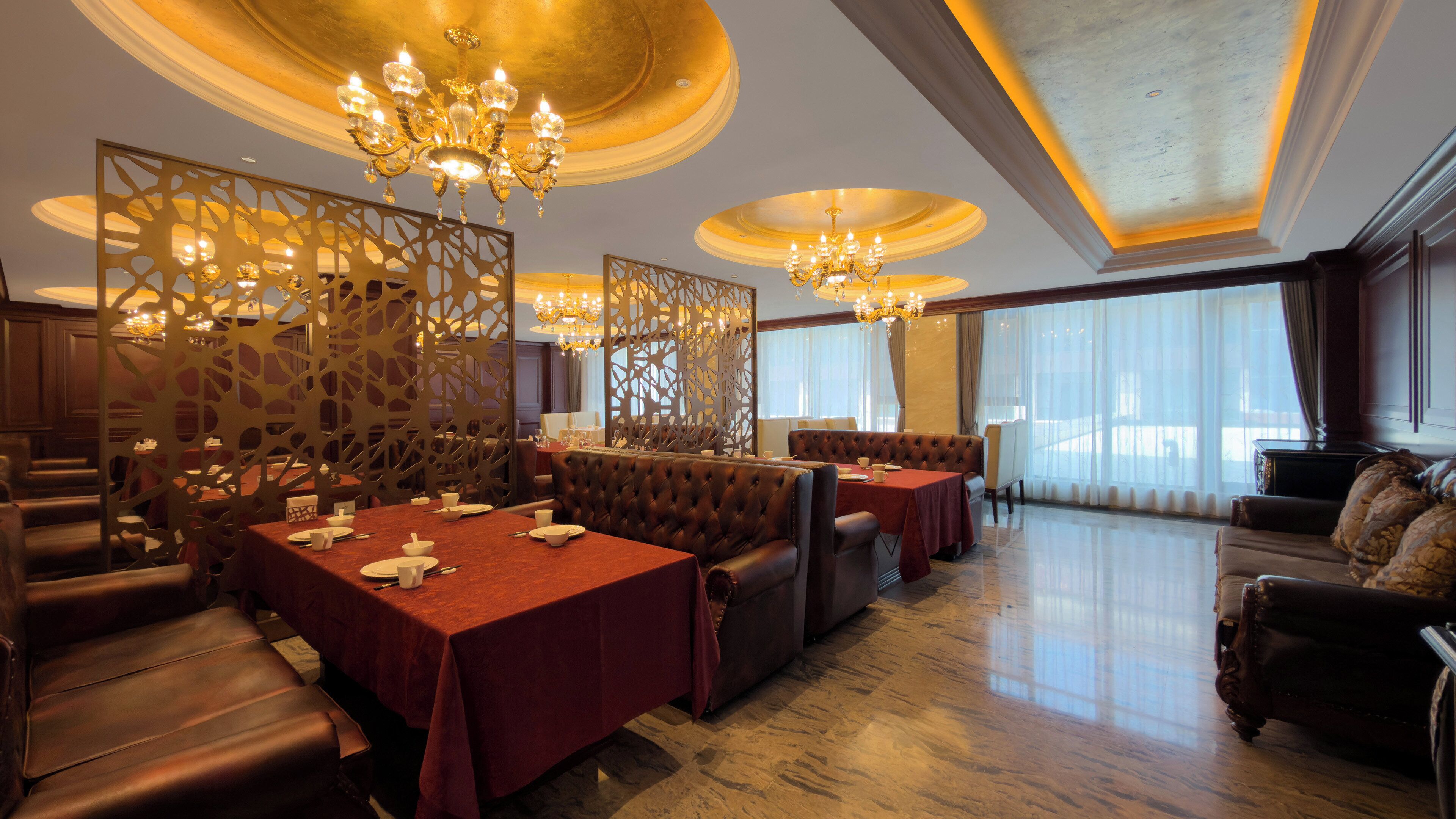 A spacious dining area with high ceilings, chandeliers, and a view of the city.